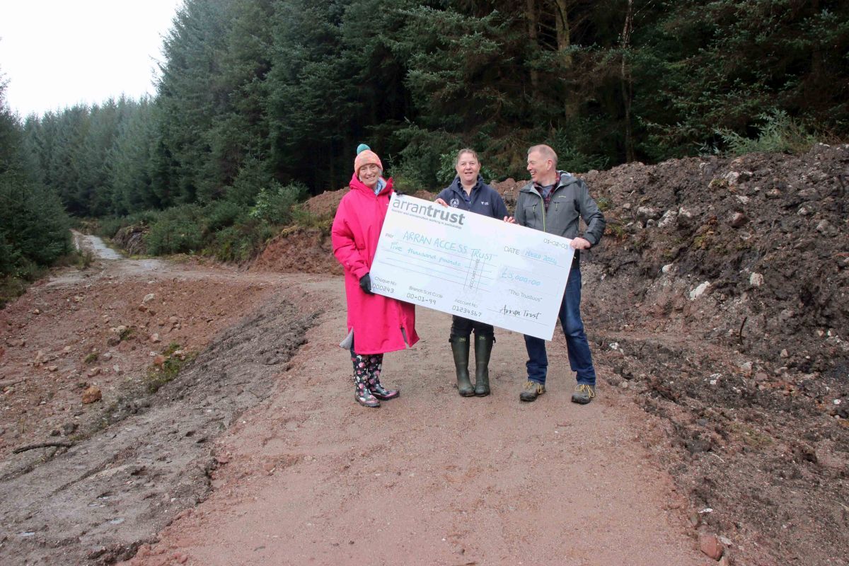 Sheila Gilmore of Arran Access Trust presents Arran Ranger Kate Sampson and Gerard Tattersfield of the Arran Bike Club with a cheque. Photograph: ARS.