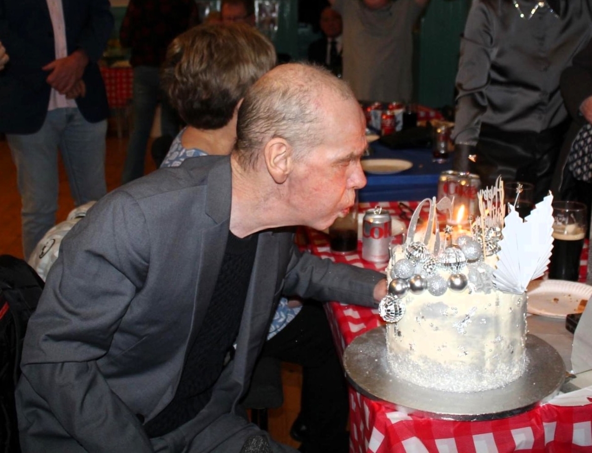 Robbie Bell blows out the candles on his cake at his surprise 70th birthday party in Furnace village hall. Photograph: Emma Irons