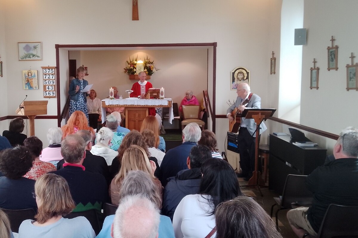 Father Noel Colford joins his parishioners in song during the celebratory mass.  Photograph: Holy Cross Church.