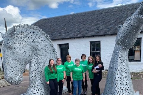 Walkers at the start of the Crinan Canal in Ardrishaig, standing beside the mini Kelpies.