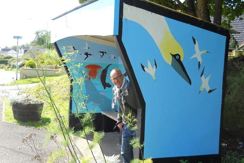 David Aitcheson in one of the bus shelters he painted and which is featured in the Heritage Tales and Trails project. Photograph: Whiting Bay Memories. 