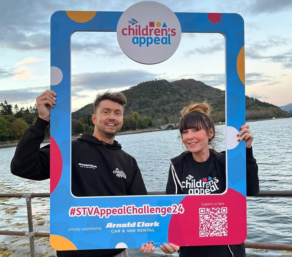 STV's Sean Batty and Laura Boyd posing for a snap with the Dun Na Cuaiche Watchtower up on the hill behind them in Inveraray.