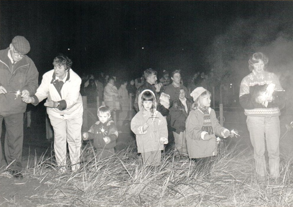 Youngsters are fascinated by their sparklers at a bonfire night celebration.