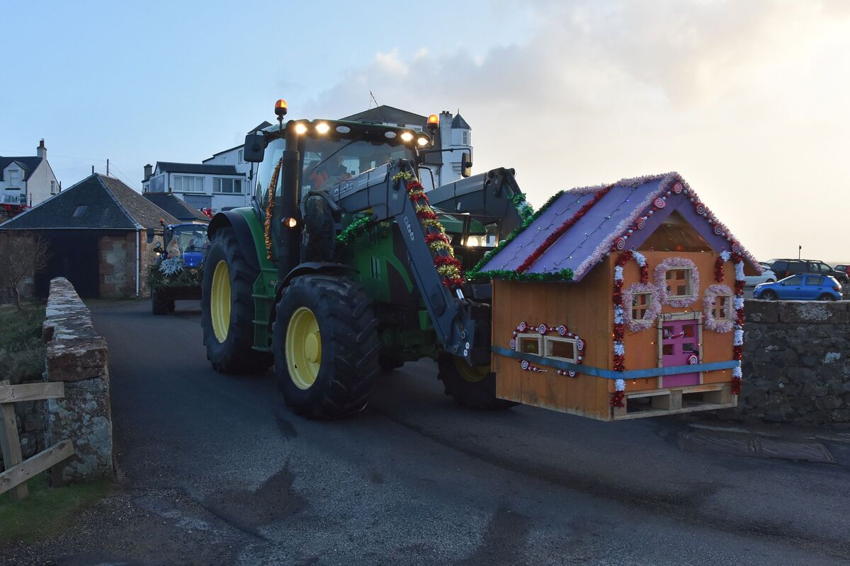 A large tractor with a gingerbread house attached to the front.