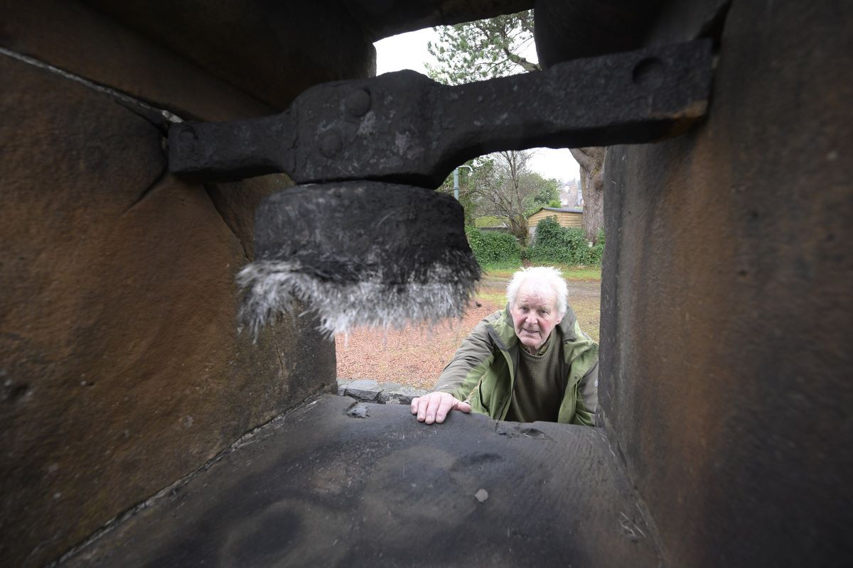 James Kennedy from Fort William Town Team inspects the burnt out bell on the Peace Cairn. Photograph: Iain Ferguson, alba.photos.