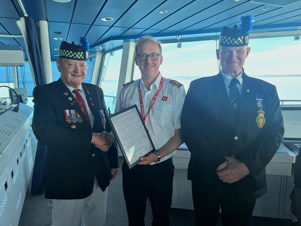MV Glen Sannox master Tobi Sogl is presented with a framed copy of Winston Churchill’s victory speech by members of the Royal British Legion. Photograph: CalMac. MV Glen Sannox master Tobi Sogl is presented with a framed copy of Winston Churchill’s victory speech by members of the Royal British Legion. Photograph: CalMac.