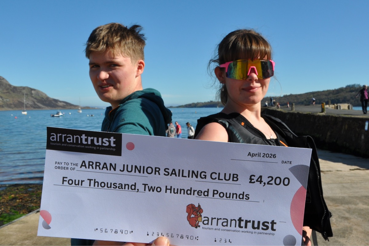 New Arran Junior Sailing dingy instructors, Alec Fraser and Rosie McNamara, with the cheque presented to the club by Arran Trust. Photograph: AJSC.