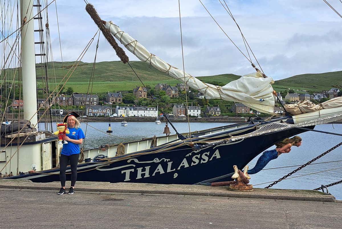 Session leader Linzi Robertson and Bookbug pose beside the tall ship Thalassa, which provided a special treat for youngsters taking part in Campbeltown Library’s Bookbug’s Big Quest celebrations.