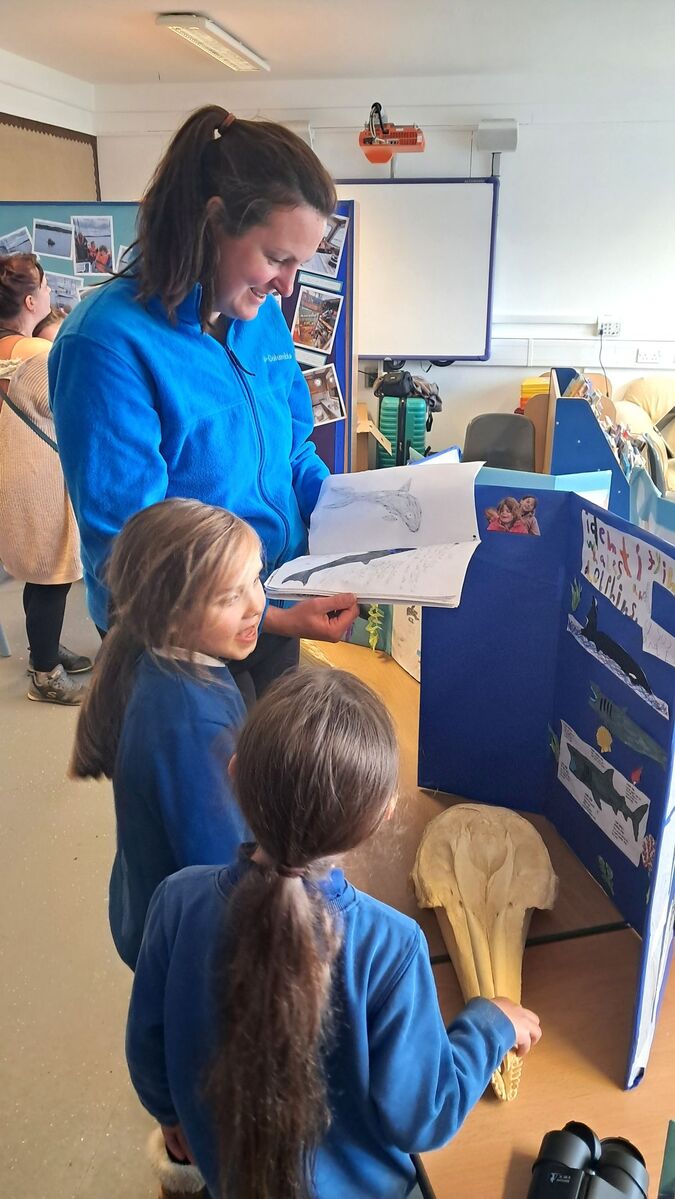 Gigha head teacher Mrs Vipurs looks over pupils’ marine conservation work during the school’s public exhibition. Photograph: HWDT.