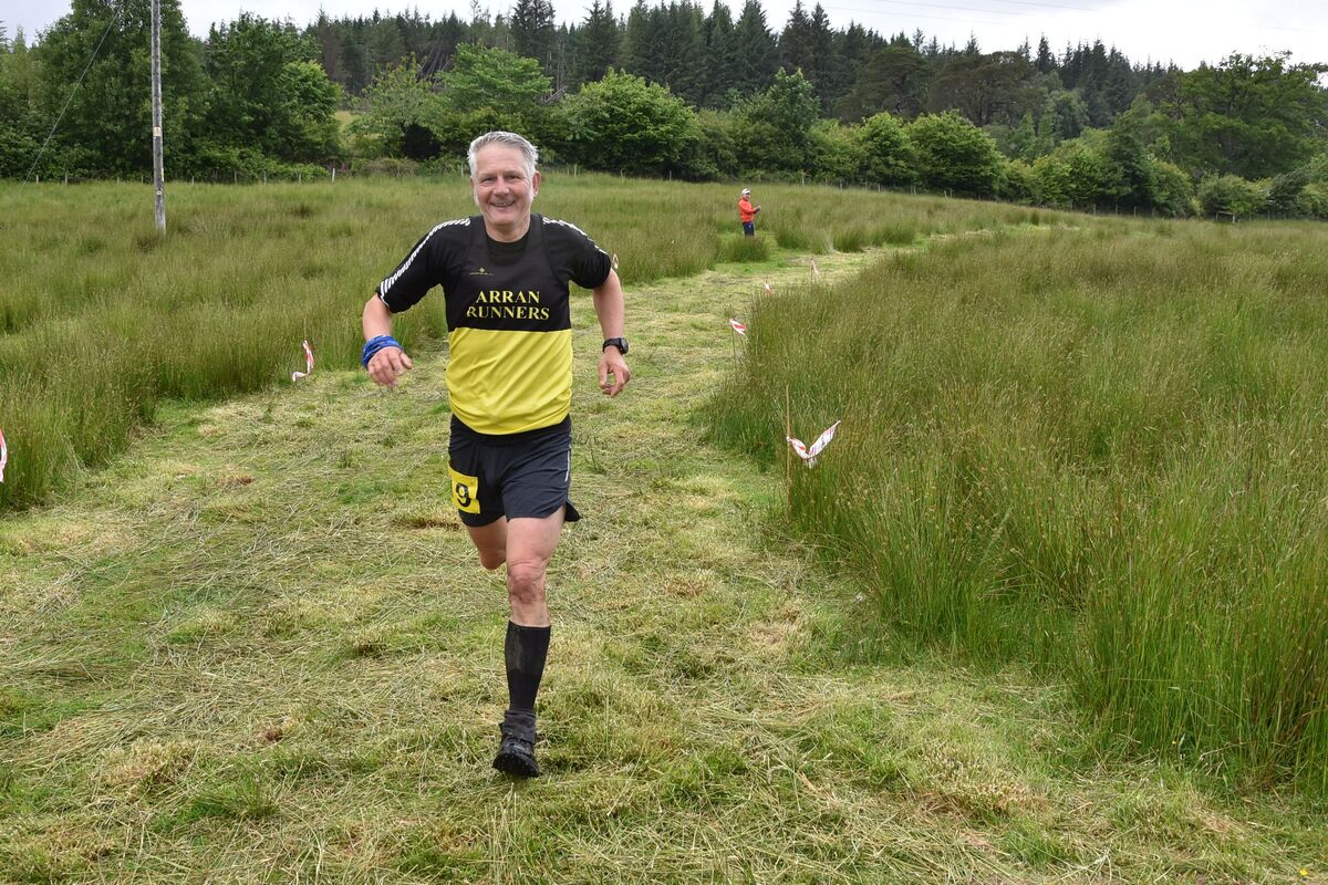 Arran Runners’ Mark Bentley crosses the finish line with a smile on his face.