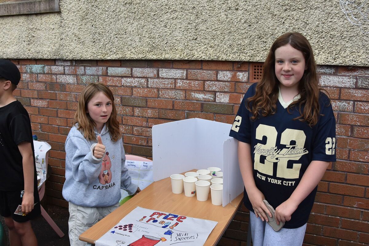 Two young girls encourage punters to try and win sweet prizes at their pong stall.