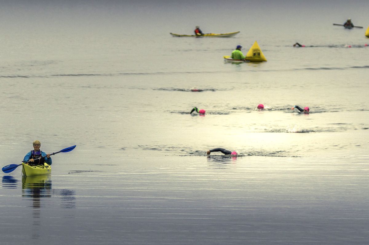 Triathletes navigate the 750m swim in the calm waters of Campbeltown Loch, supported by safety kayakers. Photograph: John Coffield.