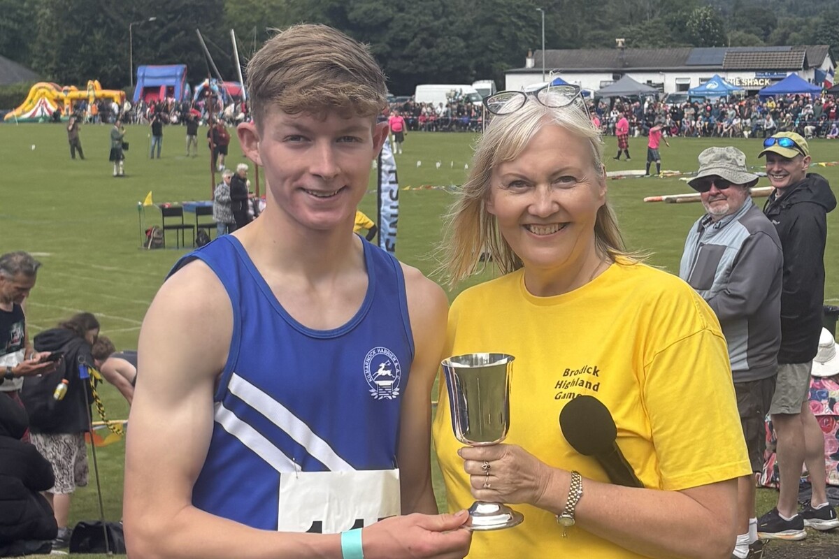 Vice chair Ailsa Weir presents Thomas Morag-Lee with the Tom Dickie Trophy for his efforts in the half mile race. Photograph: Sheila Gilmore.