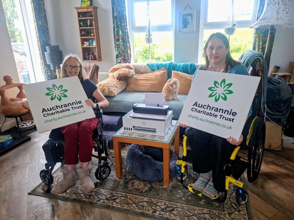 Carol Hayman, Auchrannie Charitable Trust trustee, with Disability Arran chair, Elizabeth Bell, the new printer and Ernie the cat. Photograph: ACT.