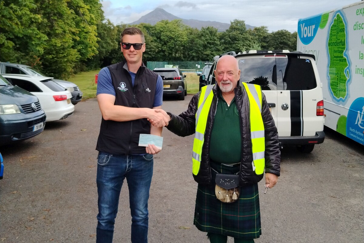 Derek Shand of Arran Runners presents Arran Mountain Rescue Team leader, Ewan McKinnon with a cheque. Photograph: Arran Runners.