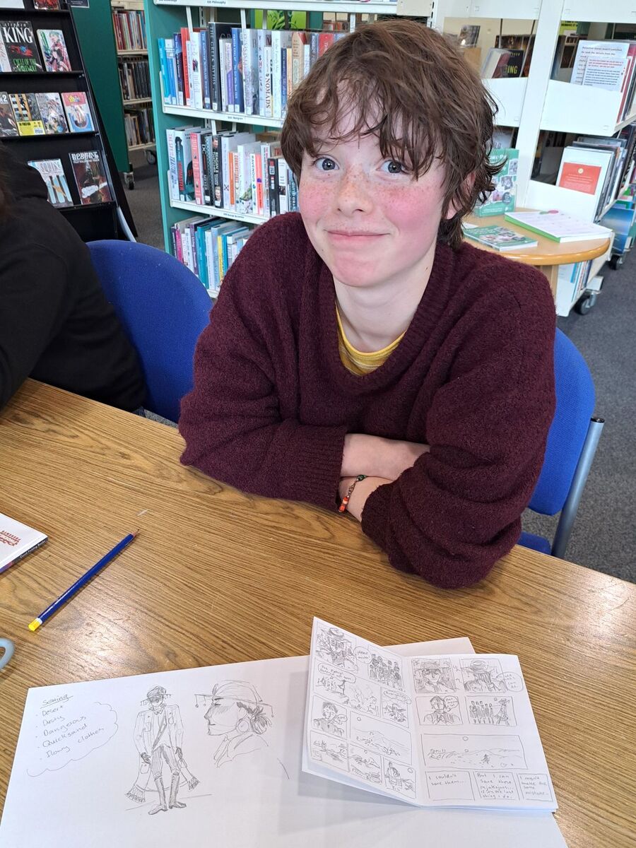 A young participant displays his mini comic artwork created during the workshop.